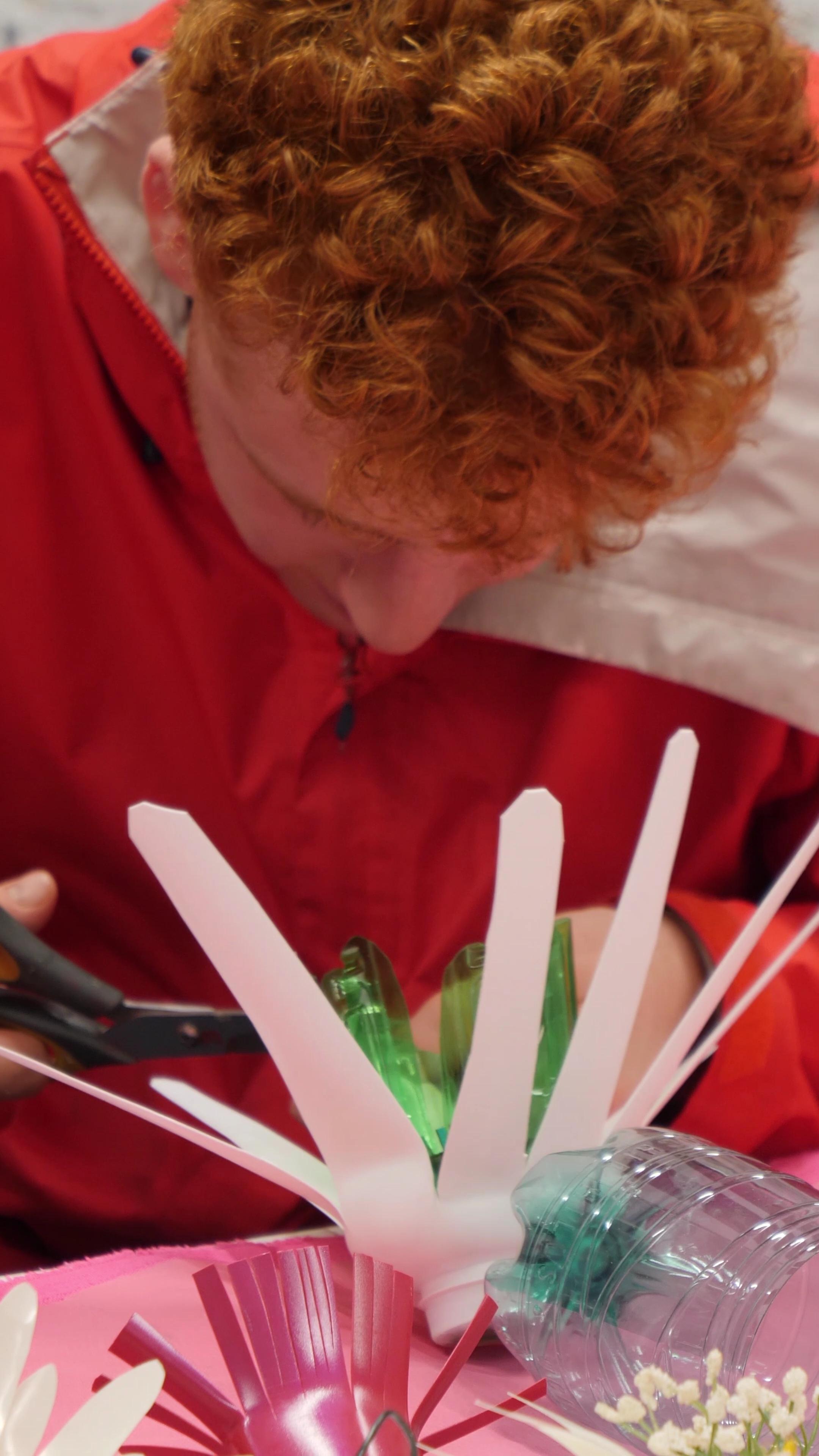 young person creating a flower from recycled plastics