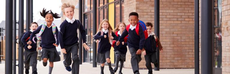 young children in school uniforms running and laughing