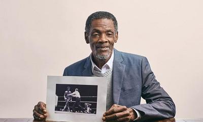 Vernon Vanriel holding a photo of himself boxing