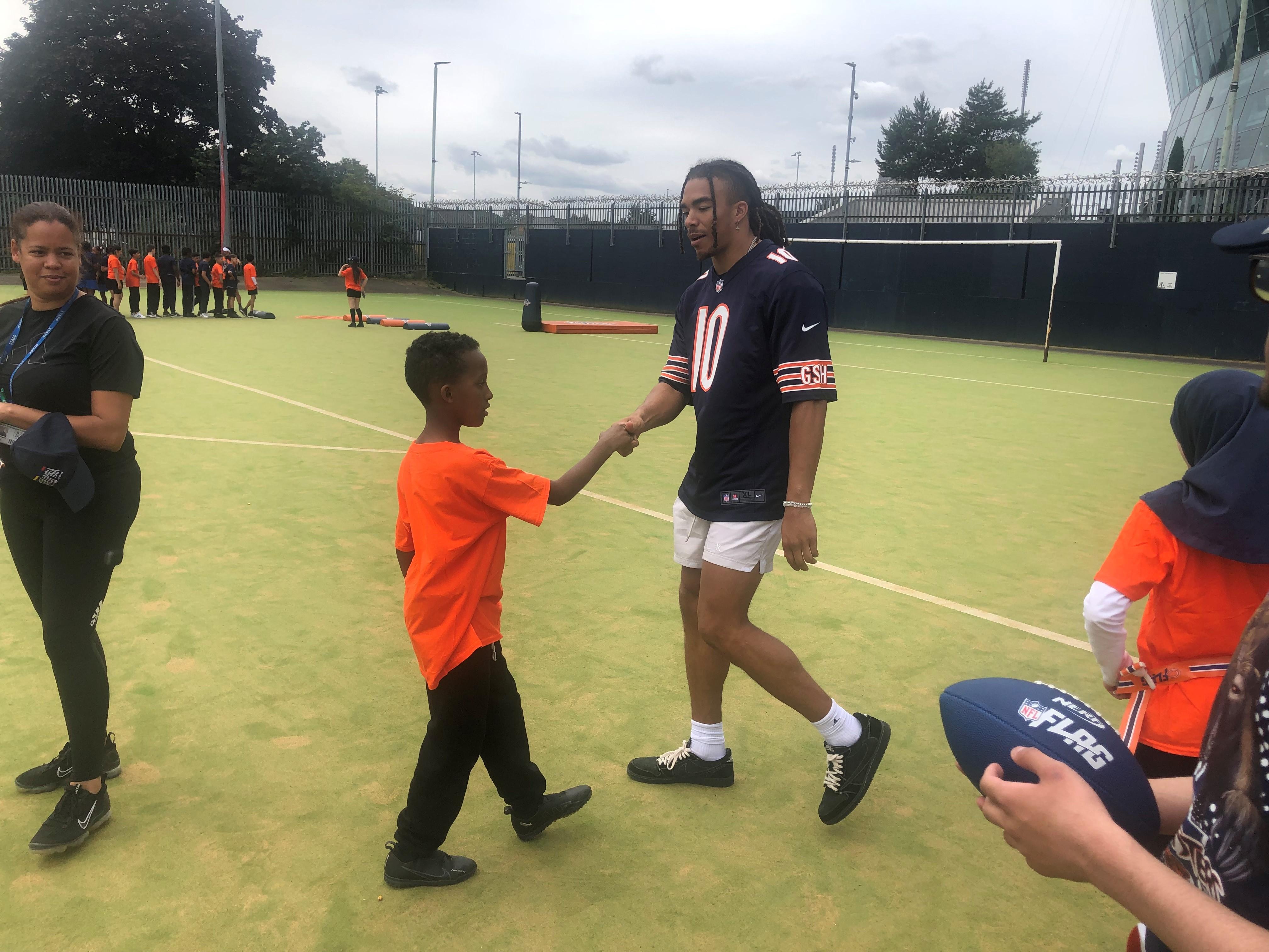 The pic is of Chicago Bears wide receiver/WR Chase Claypool shaking hands with a young pupil during the 'Mini Monsters' camp at Duke's Aldridge Academy.
