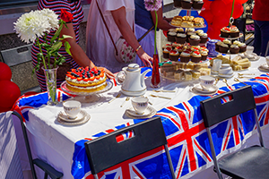 Table full of UK flags, cakes, teapots and tea cups in occasion of street party