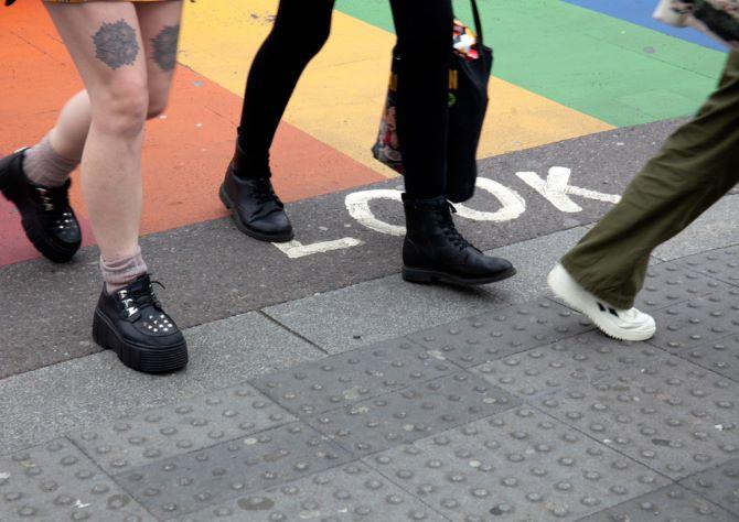 image of three young people's legs as they walk on the pavement
