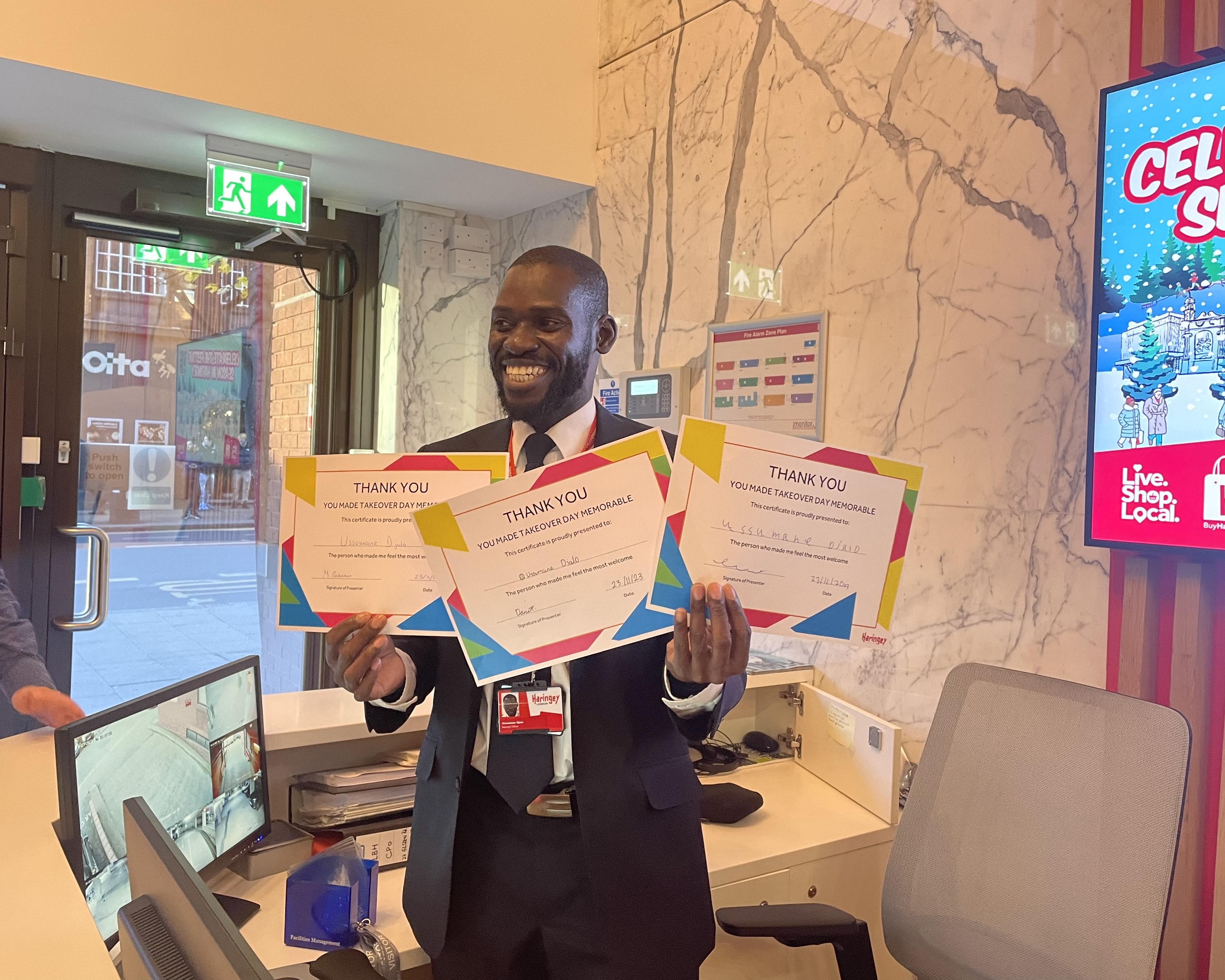 image of a man smiling holding 3 certificates