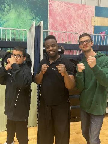 Image of 2 young people posing with a martial arts instructor