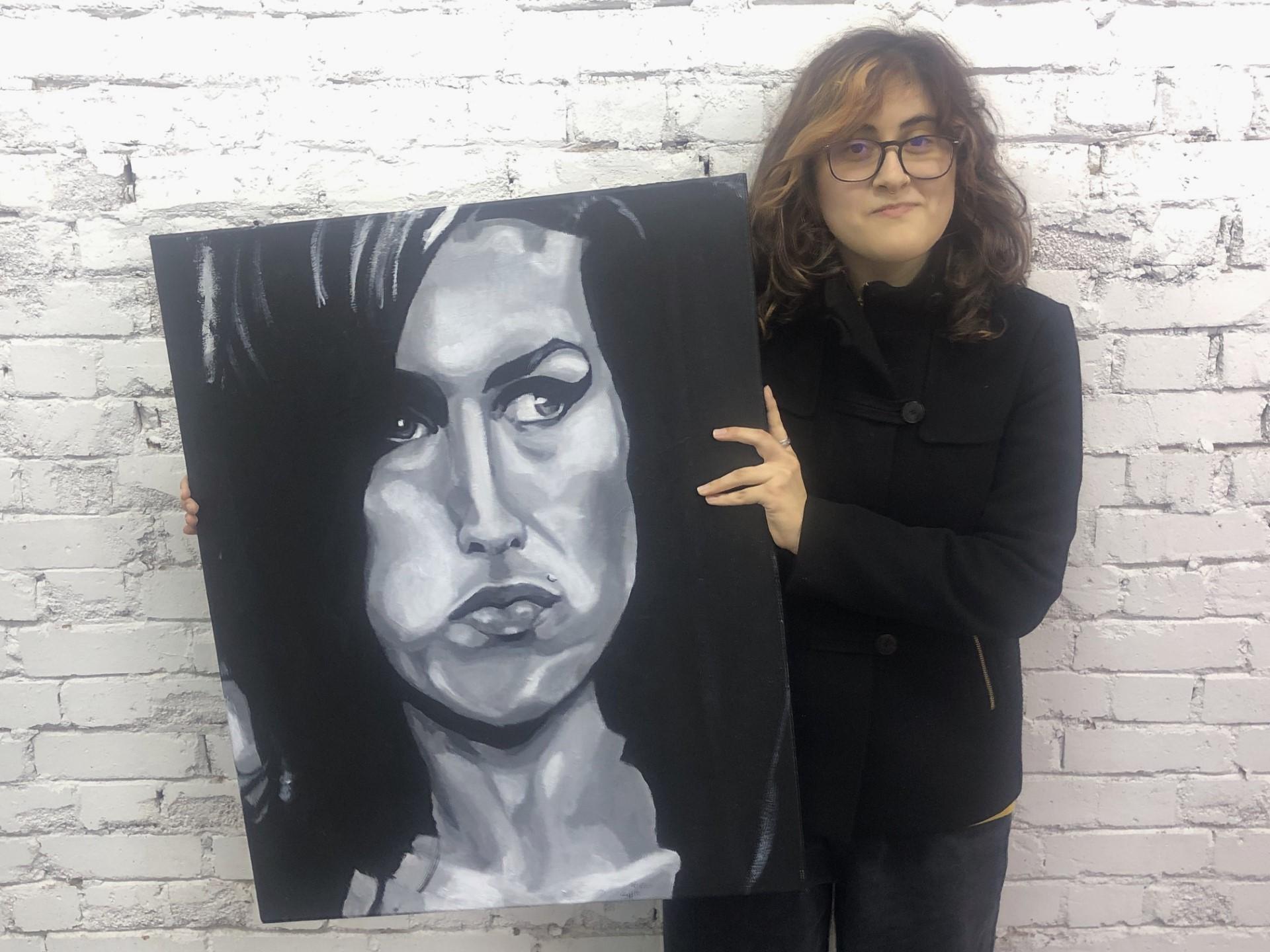 image of a young person holding their hand painted portrait of Amy Winehouse