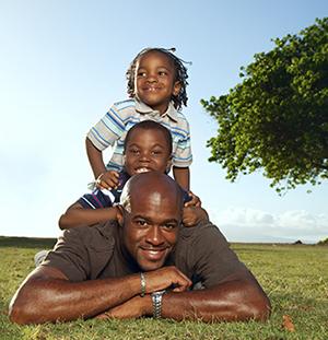 Smiling adult with 2 children lying on grass