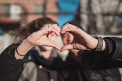 two young people holding a hand each together to form a heart-shape